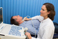 Ärztin behandelt einen Patienten mit Ultraschall
